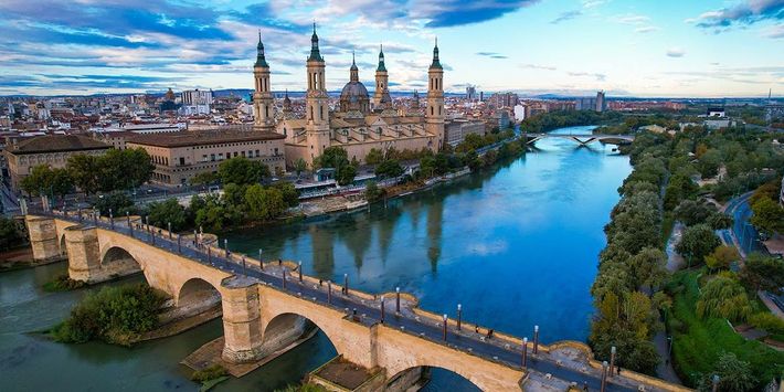 Saragossa am Ebro: Die Basílica del Pilar prägt seit Jahrhunderten das Stadtbild und ist ein zentraler Ort auf dem Weg des Apostels Jakobus. | Foto: Mike-Workmann/AdobeStock Panoramablick auf Saragossa mit der Basílica del Pilar am Fluss Ebro, einem bedeutenden Wallfahrtsort auf dem Jakobsweg.